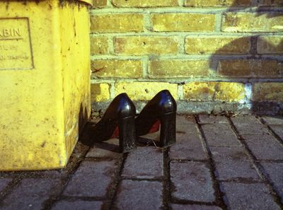 Yellow. Abandoned high heels by a bin