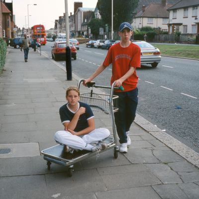 boy pushing girl on a supermarket platform trolley